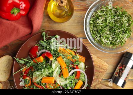 Deliziosa insalata di verdure con microgreens servita su un tavolo di legno, piatto Foto Stock