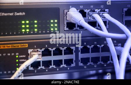 Gli switch di rete e i cavi ethernet nell'armadietto rack sono in primo piano Foto Stock