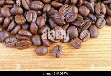 Mucchio di fagioli di caffè arrosto su sfondo di legno Foto Stock