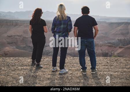 Tre persone che guardano al Grand Canyon da un punto di vista, ventoso Foto Stock