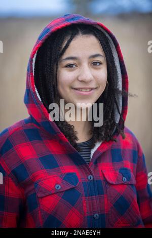 ritratto di giovane donna biraciale sorridente con trecce e cappuccio Foto Stock