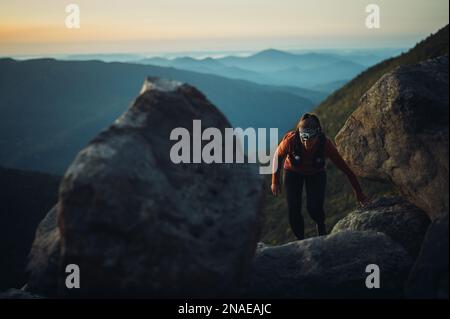 Donna escursioni tra massi all'alba in montagne bianche Foto Stock