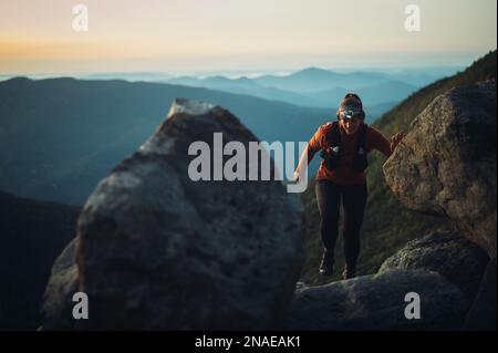 Donna escursioni tra massi all'alba in montagne bianche Foto Stock