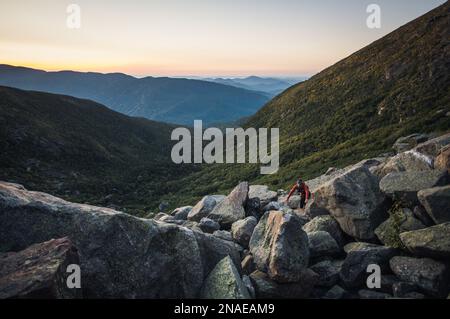 Donna escursioni tra massi all'alba in montagne bianche Foto Stock