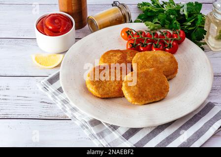 cotolette di pollo in un piatto su uno sfondo di legno chiaro Foto Stock