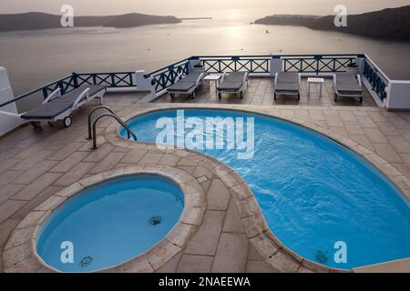 Lettini e piscine sulla terrazza nel villaggio di Imerovigli, con una splendida vista del tramonto sulla caldera di Santorini. Grecia Foto Stock