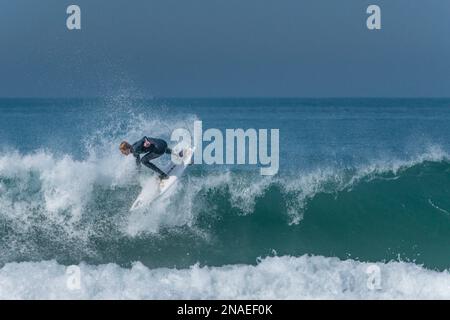 Spettacolare azione di surf mentre un surfista cavalca sulla cresta di un'onda a Fistral in Cornovaglia nel Regno Unito. Foto Stock