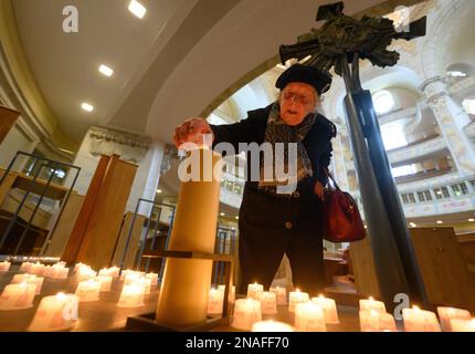 Dresda, Germania. 13th Feb, 2023. Karla Lorenz, 88 anni di Dresda residente e sopravvissuto ai bombardamenti del 1945, accende una cosiddetta luce della Pace sotto la croce torre distrutta della Frauenkirche nel 78th° anniversario della distruzione di Dresda nella seconda guerra mondiale Il 13 febbraio, la capitale dello stato di Dresda commemora la distruzione della città nella seconda guerra mondiale 78 anni fa. Il 13 e 14 febbraio 1945, i bombardieri alleati riducevano il centro della città sull'Elba a macerie. Fino a 25.000 persone hanno perso la vita. Credit: Robert Michael/dpa/Alamy Live News Foto Stock