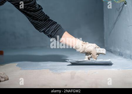 lavoro manuale con impermeabilizzazione bagno con cazzuola Foto Stock