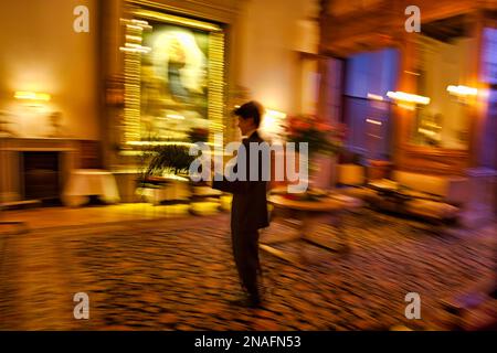 Il cameriere prepara una sala da pranzo rinfrescando le composizioni floreali in un lussuoso hotel nelle Alpi svizzere, St. Moritz, Svizzera Foto Stock