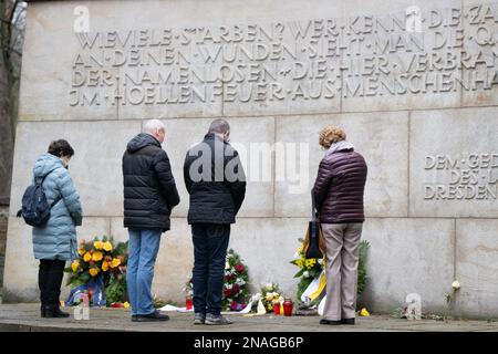 Dresda, Germania. 13th Feb, 2023. La gente si trova davanti alle corone di fiori nella lapide commemorativa per le vittime del bombardamento del 13 e 14 febbraio 1945, presso il cimitero di Heidefriedhof. Il 13 febbraio, la capitale dello stato Dresden commemora la distruzione della città durante la seconda guerra mondiale 78 anni fa. Il 13 e 14 febbraio 1945, i bombardieri alleati riducevano il centro della città sull'Elba a macerie. Fino a 25.000 persone hanno perso la vita. Credit: Sebastian Kahnert/dpa/Alamy Live News Foto Stock
