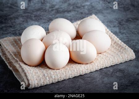 Uova di pollo su un asciugamano beige su sfondo grigio Foto Stock