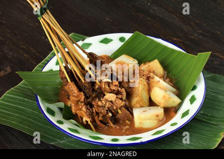 Sate Padang. Satay di manzo piccante di Padang, West Sumatra. Servito con salsa di curry piccante e Longong o ketupat. Su piastra di smalto Foto Stock