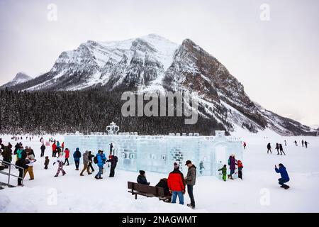 I visitatori del lago Louise pattinano e ammirano i castelli di ghiaccio con Fairview Mountain sullo sfondo del Banff National Park Foto Stock