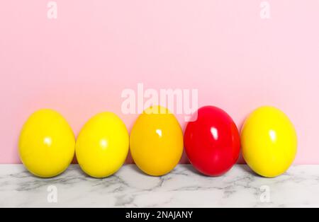 Uova di Pasqua su tavola di marmo bianco su sfondo rosa, spazio per il testo Foto Stock