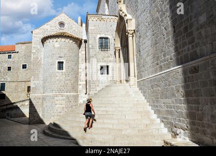 Donna in cappello salendo le scale della chiesa di San Domenico, monastero dominicano nel centro storico di Dubrovnik, Croazia. Foto Stock