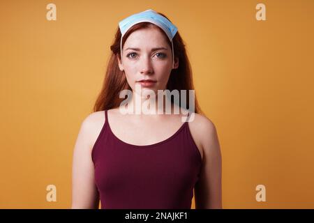 giovane donna che indossa una maschera medica errata sulla testa uso come scarpetta - uso improprio della corona protettiva maschera di coronavirus covid Foto Stock