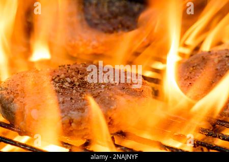 Grigliare al fuoco hamburger fatti in casa sul barbecue. Cucina estiva all'aperto Foto Stock