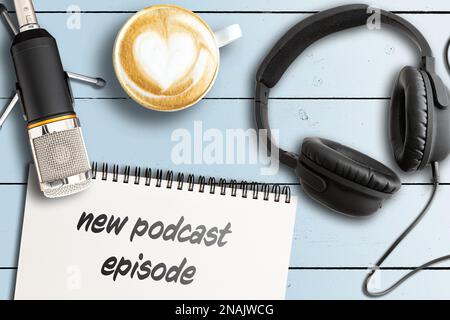 Direttamente sopra la vista delle parole NUOVO PODCAST EPISODIO su blocco note con microfono e cuffie su tavolo di legno, podcasting concetto Foto Stock