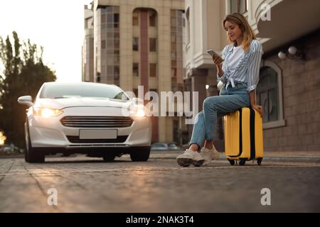 Donna che ordina un taxi con smartphone in strada Foto Stock