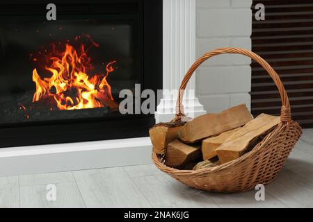 Cestino di vimini con legno vicino al caminetto in camera Foto stock - Alamy