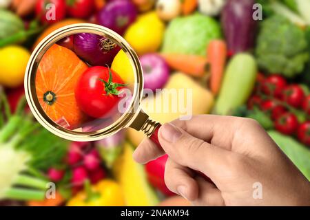 Donna con lente d'ingrandimento che esplora le verdure, primo piano. Rilevamento di veleni Foto Stock