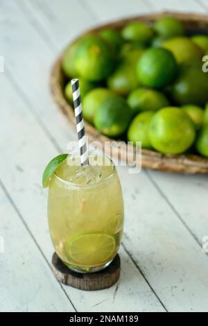 Bevanda brasiliana Caipirinha su un tavolo di legno bianco con limoni sullo sfondo. Foto Stock