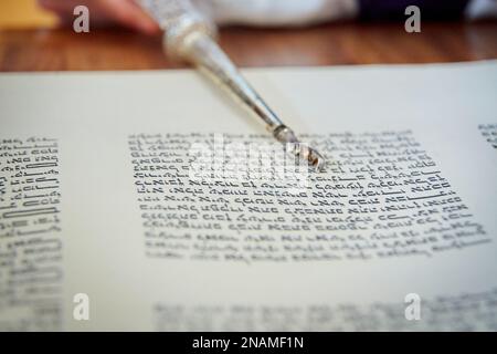 Primo piano di Yad che indica le lettere ebraiche in Torah Scroll Foto Stock