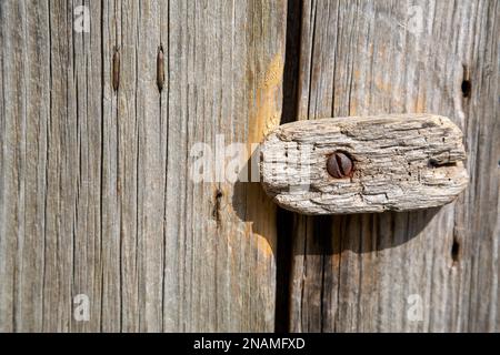 Vecchio bullone di bloccaggio in legno intemperiato sulla porta del fienile in legno Foto Stock