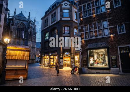 Foto delle facciate di una strada medievale al crepuscolo, con negozi e boutique, con un'architettura tedesca d'epoca, nel centro della città di Aquisgrana, Germania. Foto Stock