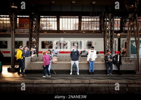 Immagine degli uomini in attesa di un treno sulle piattaforme della stazione ferroviaria di Koln hauptbahnhof, indossando maschere facciali durante il Coronavirus Covid 19 salute cris Foto Stock