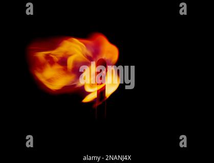 Macro shot di un fiammiferi di sicurezza in legno che brucia con una fiamma colorata e luminosa su sfondo nero Foto Stock