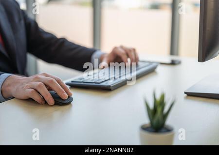 Concetto di business, tecnologia e luogo di lavoro. Primo piano di un uomo d'affari caucasico computer da scrivania con mouse e tastiera su tavolo di legno. Foto Stock