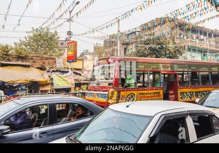 Un autobus locale martoriato e auto nel traffico tipico occupato: scena di strada a Fariapukur, Shyam Bazar, un sobborgo di Kolkata, Bengala Occidentale, India Foto Stock