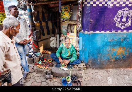 mender locale che ripara scarpe e lustra scarpe in una piccola bancarella sul marciapiede a Fariapukur, Shyam Bazar, Kolkata, Bengala Occidentale, India Foto Stock