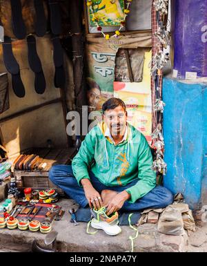 mender locale che ripara scarpe e lustra scarpe in una piccola bancarella sul marciapiede a Fariapukur, Shyam Bazar, Kolkata, Bengala Occidentale, India Foto Stock