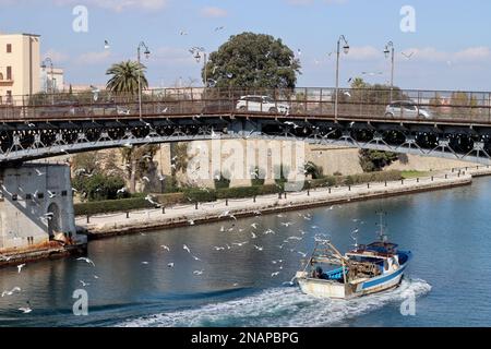 Taranto swing ponte con barca da pesca di ritorno al porto circondato da decine di gabbiani. Puglia, Italia Foto Stock