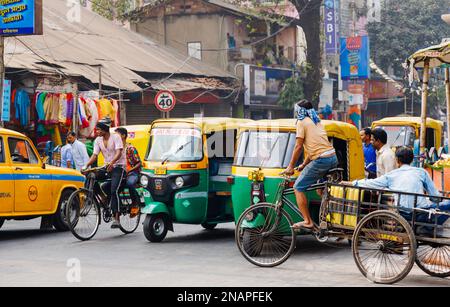 Scena di strada in Kanna, Shyam Bazar, Kolkata suburbana, Bengala Occidentale, India con carrello triciclo e autorickshaws (tuktuks) nella strada Foto Stock