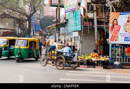 Scena di strada in Kanna, Shyam Bazar, Kolkata suburbana, Bengala Occidentale, India con carrello triciclo e autorickshaws (tuktuks) nella strada Foto Stock