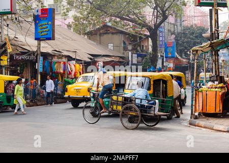 Scena di strada in Kanna, Shyam Bazar, Kolkata suburbana, Bengala Occidentale, India con carrello triciclo e autorickshaws (tuktuks) nella strada Foto Stock