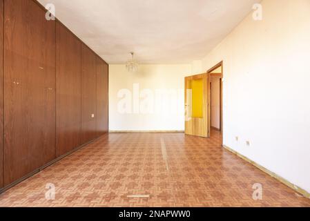 Soggiorno vuoto di una vecchia casa con pavimento in rovere e pareti rivestite in legno Foto Stock