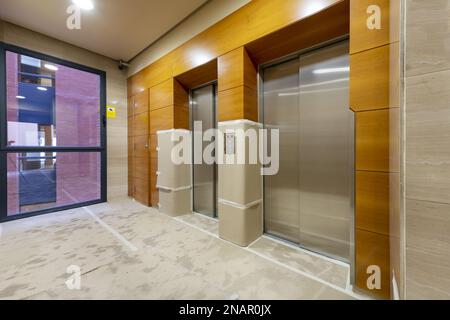 Area ascensore di un edificio di uffici con pareti e pavimenti ricoperti di cartone in fase di costruzione Foto Stock