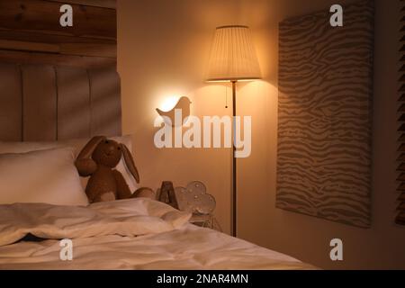 Lampade luminose vicino al letto nella stanza dei bambini di notte Foto Stock