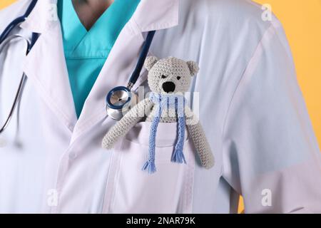 Pediatra con orso giocattolo e stetoscopio su sfondo giallo, primo piano  Foto stock - Alamy