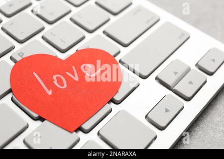 Cuore di carta con amore parola su laptop, primo piano Foto Stock