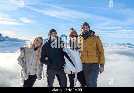 Un primo piano di un gruppo di amici con le montagne con le cime innevate in una soleggiata giornata invernale Foto Stock