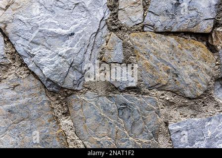 Muro con pietre di ardesia disparate unite con Malta di cemento tra i giunti Foto Stock