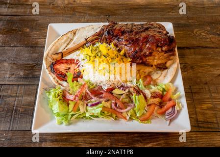 Un piatto meraviglioso con una coscia di agnello arrosto con insalata, riso con salsa e matzo Foto Stock