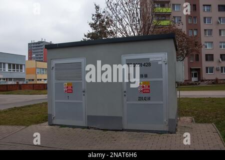 Edificio del locale dei trasformatori elettrici con porte grigie e segnali di pericolo gialli contro il cielo blu nella città di Nitra in Slovacchia Foto Stock