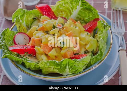 Pollo all'incoronazione con insalata mista in un piatto blu. Foto Stock